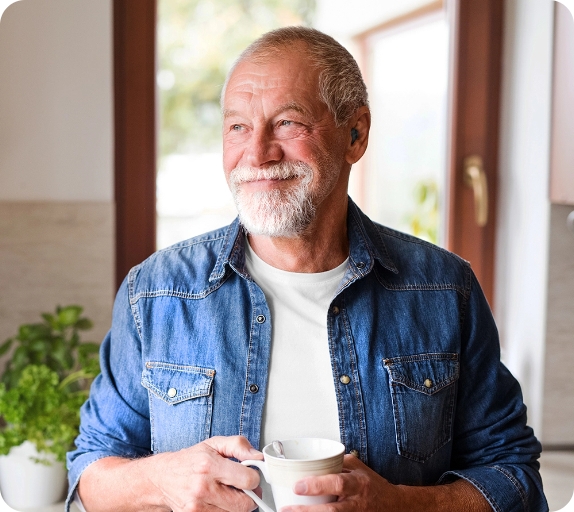 Elderly man with a beard enjoying a cup of coffee.